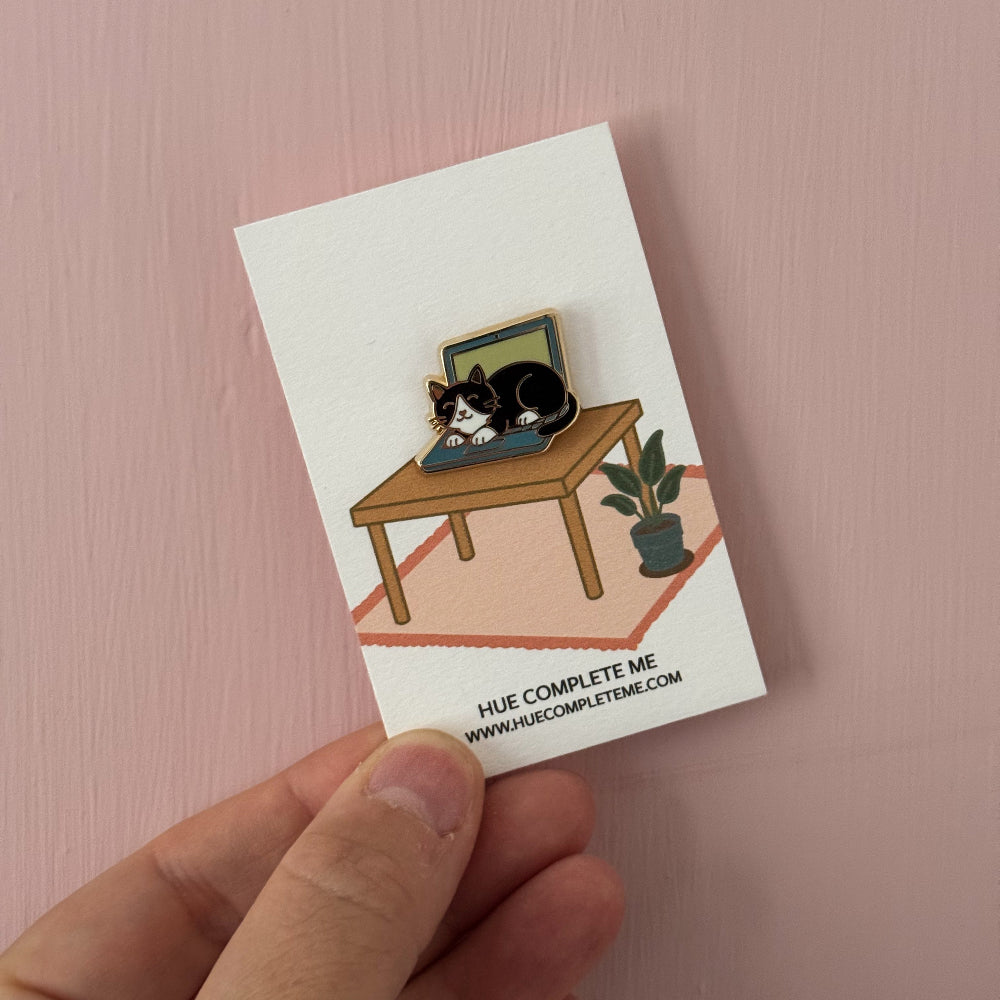 cat on a laptop enamel pin on an illustrated card backing 
