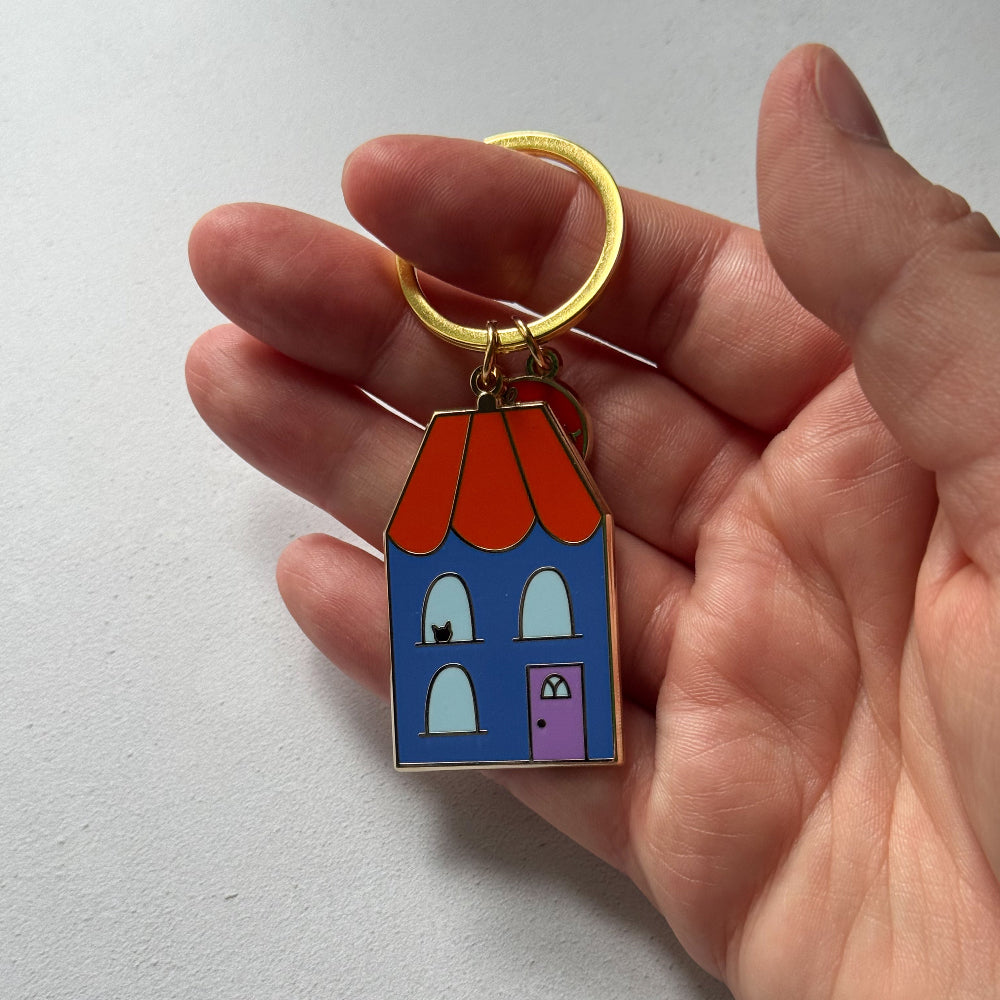 House-shaped keychain held in a hand against a light gray background