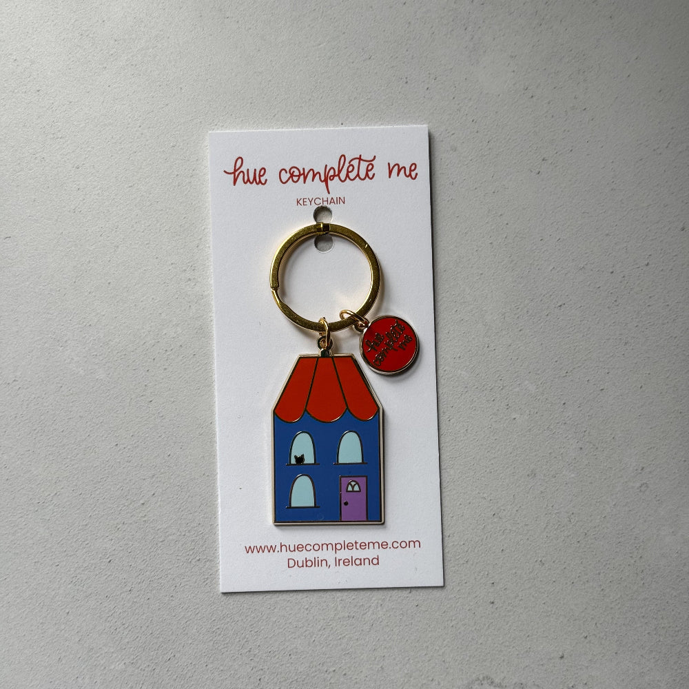 Keychain with house design on a card against a gray background
