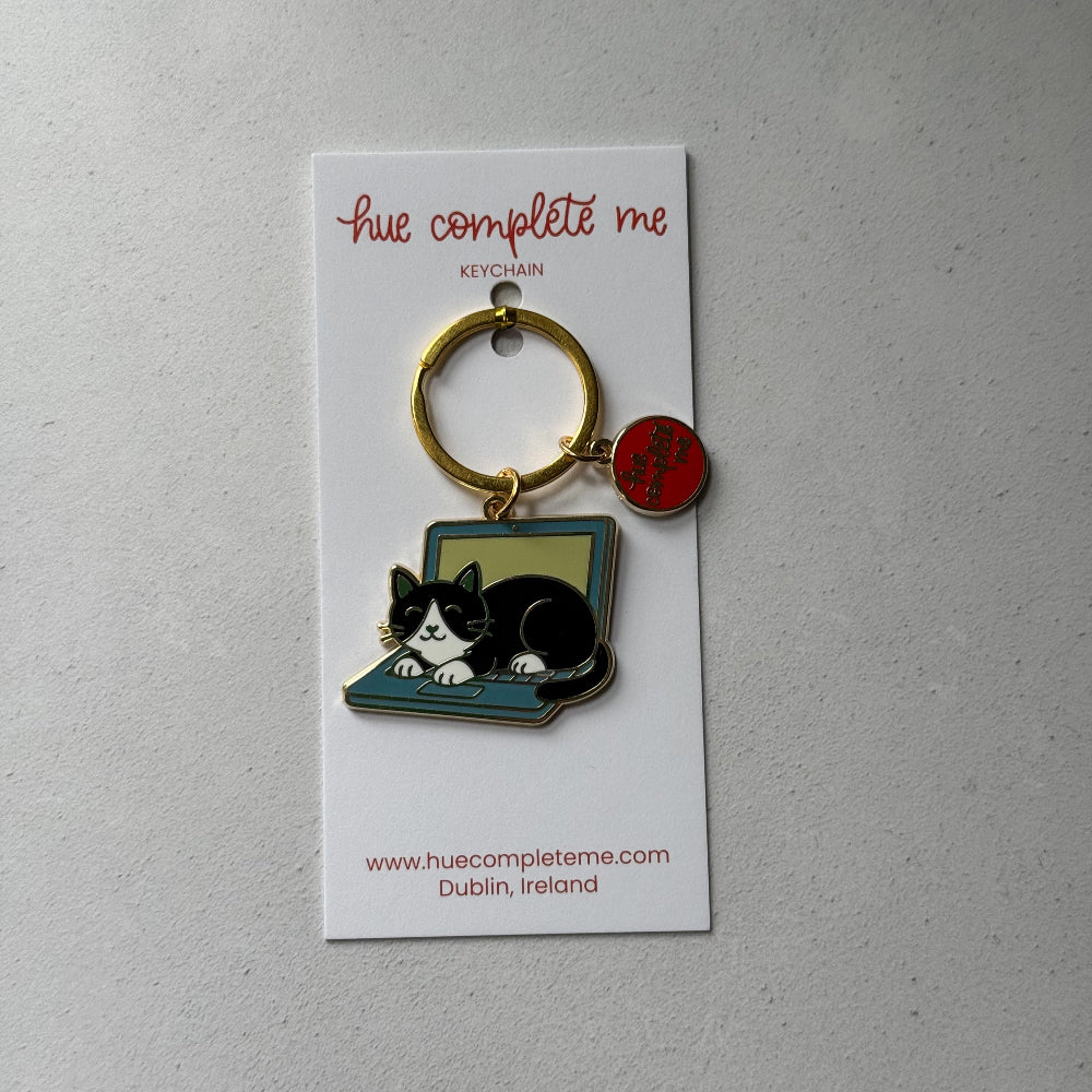 Keychain with a cat design on a white card with branding text, against a light gray background.