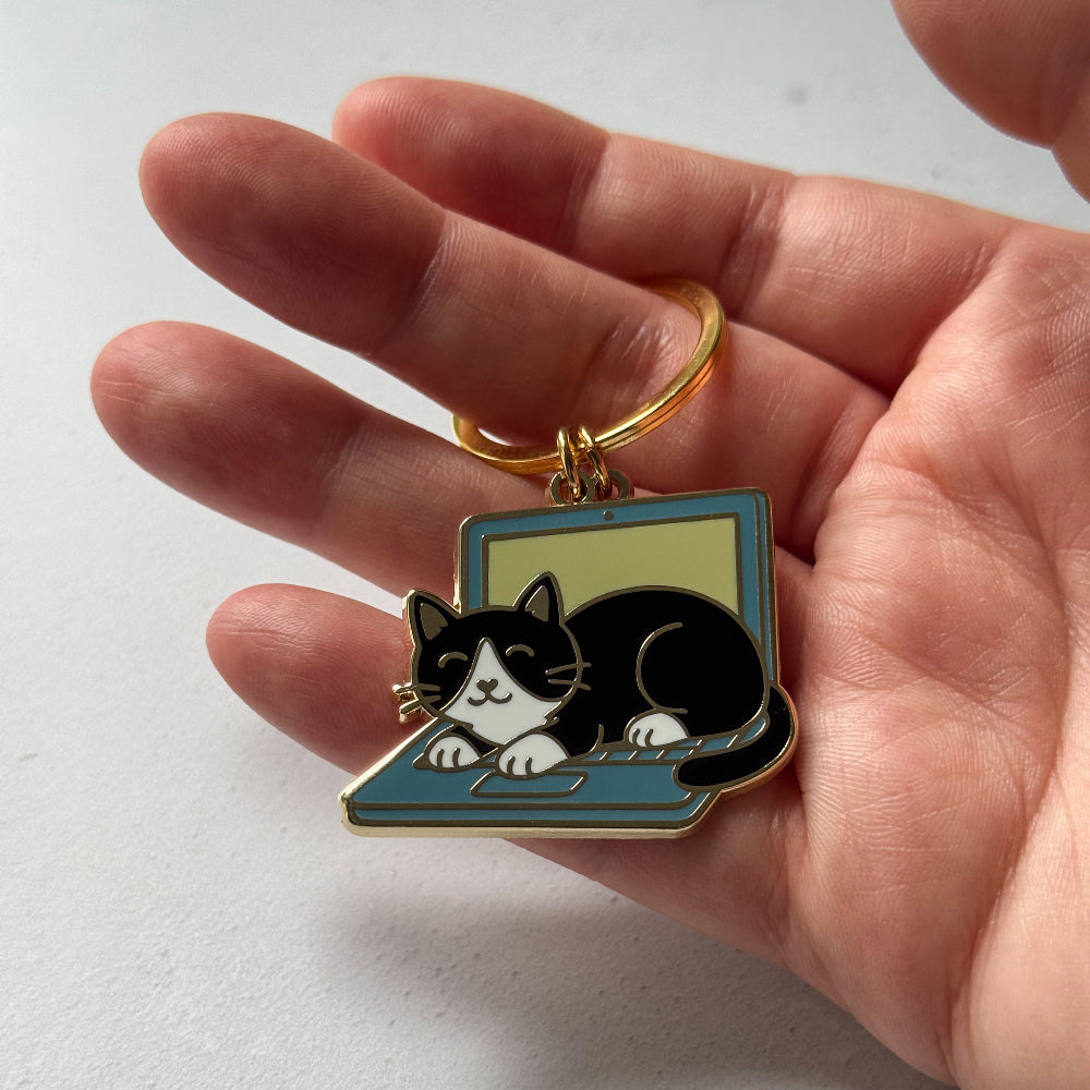 Keychain with a cat design held in a hand on a white background