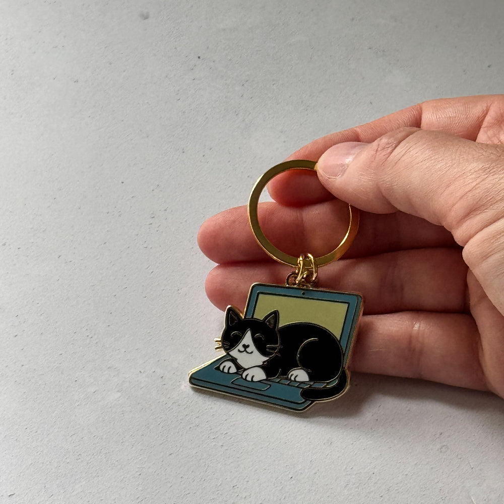 Keychain with a cat design held by a hand on a light gray background