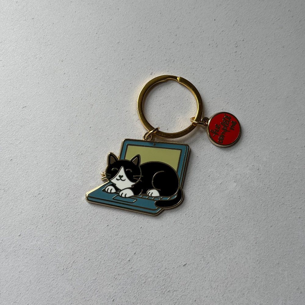 Keychain with a cat on a laptop design on a light gray background